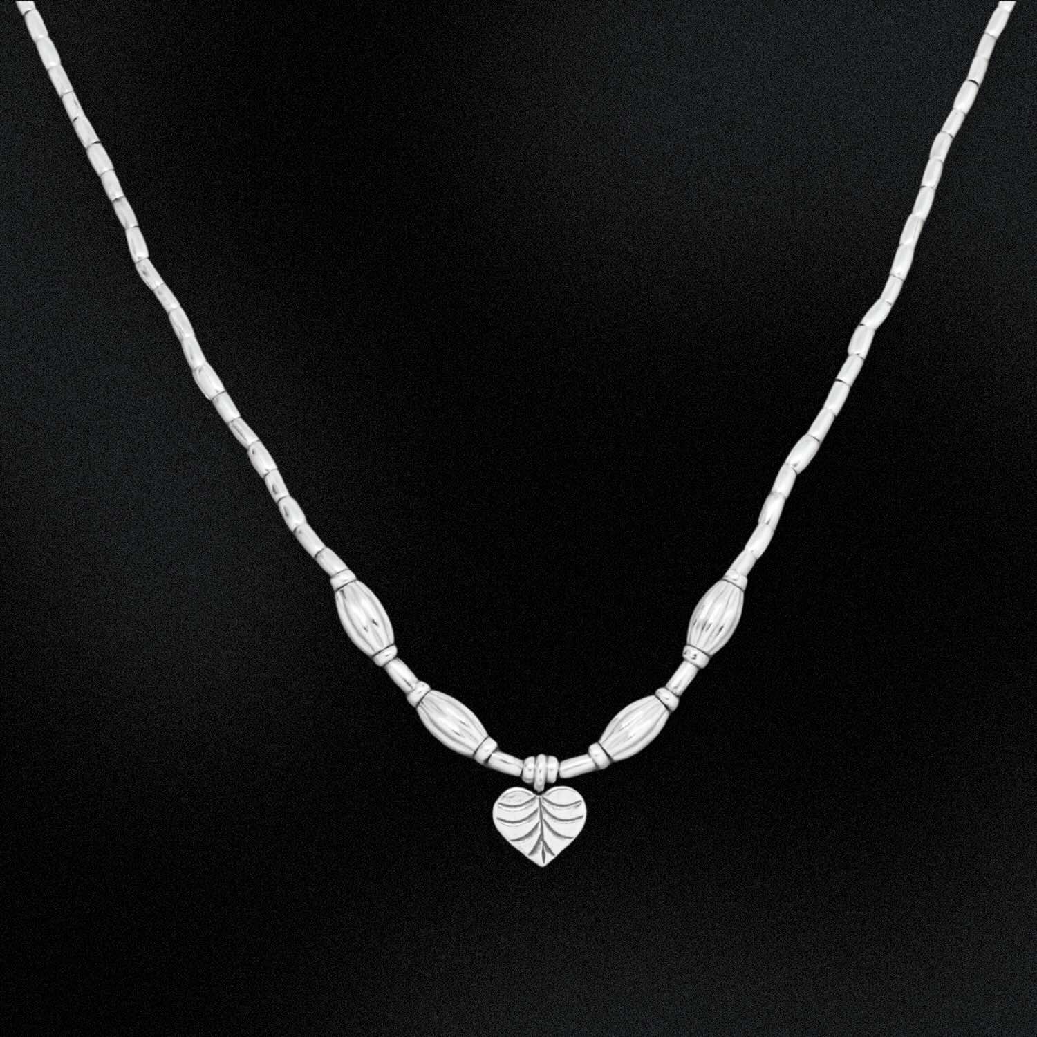 Silver necklace with a leaf pendant on a black background