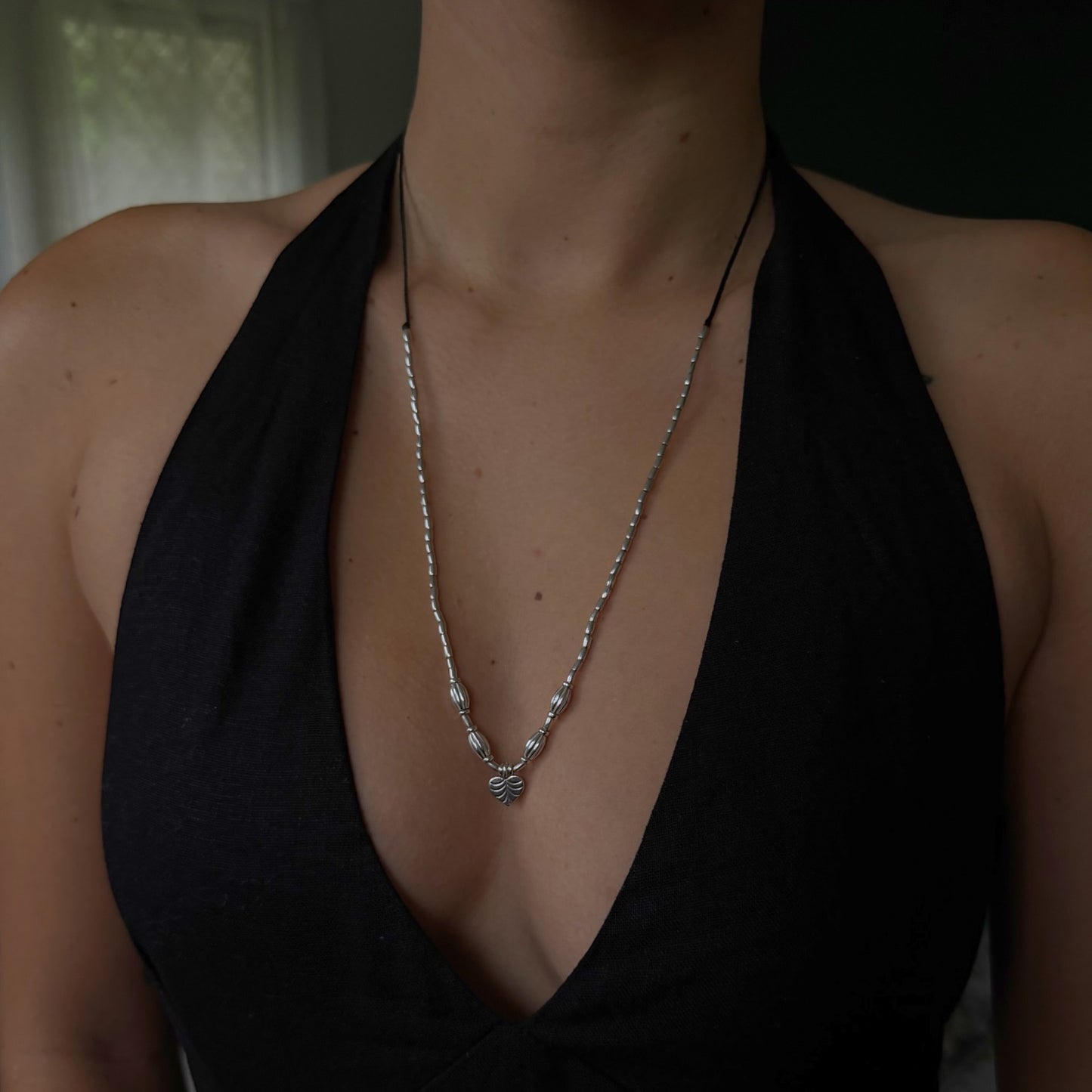 Person wearing a black halter top with a necklace