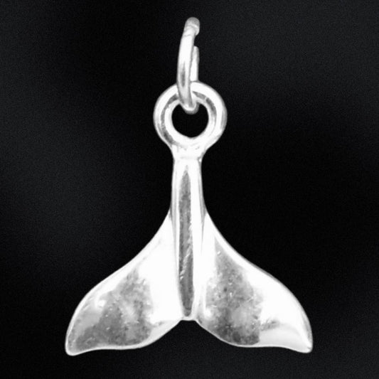 Silver whale tail charm on a black background