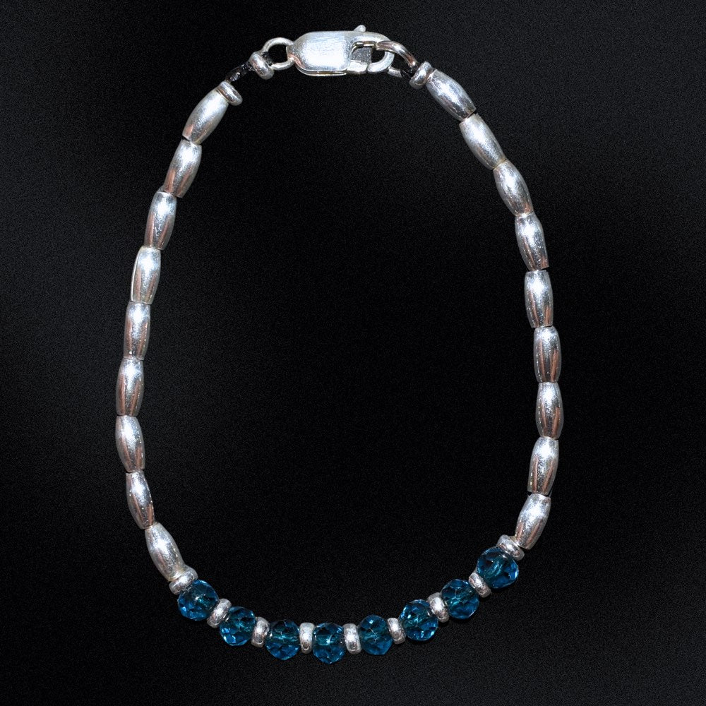 Introducing the Azure Essence Silver Beaded Bracelet - the perfect accessory to complete any outfit. The centre detail of the bracelet features stunning faceted glass rondelle blue beads that catch the light and sparkle brilliantly. Surrounding these gems are delicate silver beads, adding a touch of sophistication and elegance to the design.