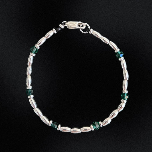 Introducing the Emerald Essence Silver Beaded Bracelet - the perfect accessory to complete any outfit. The centre detail of the bracelet features stunning faceted glass rondelle green beads that catch the light and sparkle brilliantly. Surrounding these gems are delicate silver beads, adding a touch of sophistication and elegance to the design.