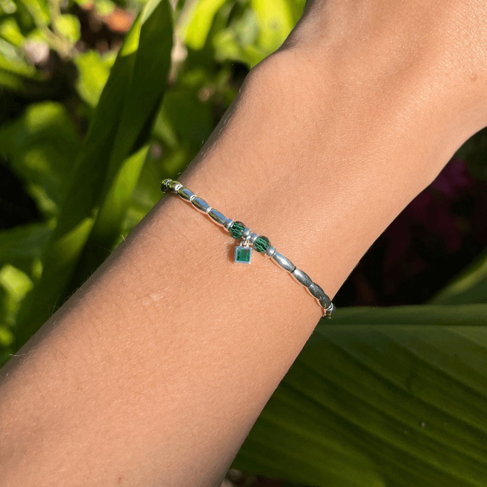 Handcrafted from premium quality sterling silver and embellished with exquisite silver beads, this stunning bracelet boasts a captivating green charm at its centre, surrounded by two alluring green beads on either side. Perfect for those who love a pop of green in their accessories.  To finish the look, the beads are threaded onto a sturdy waxed cord that has been finished with a sleek lobster clasp, making it effortless to wear and comfortable to keep on for hours.