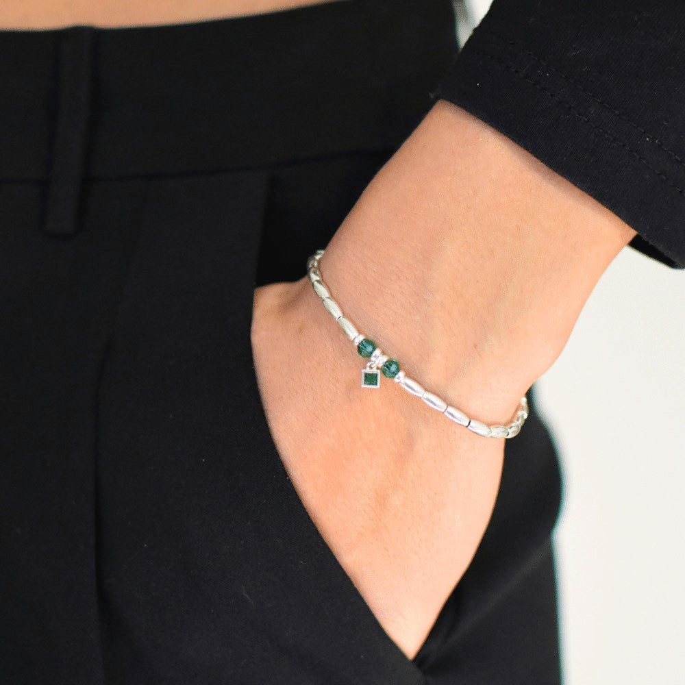 Handcrafted from premium quality sterling silver and embellished with exquisite silver beads, this stunning bracelet boasts a captivating green charm at its centre, surrounded by two alluring green beads on either side. Perfect for those who love a pop of green in their accessories.  To finish the look, the beads are threaded onto a sturdy waxed cord that has been finished with a sleek lobster clasp, making it effortless to wear and comfortable to keep on for hours.