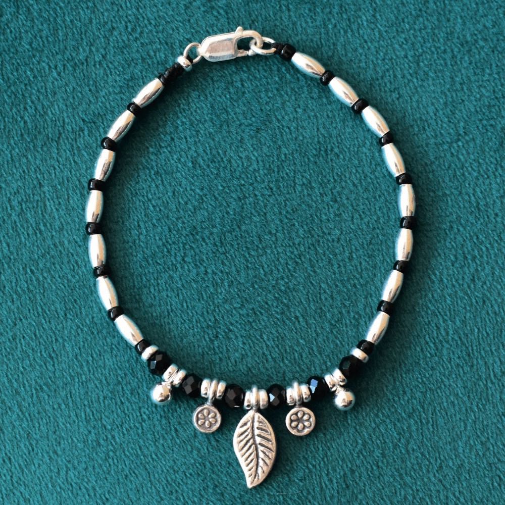 The Leafy Midnight Bloom Beaded Bracelet is not only a stunning piece of jewellery, but it is also a meaningful and symbolic addition to your collection. The leaf charm represents growth and transformation, while the daisy charms are a symbol of innocence and purity.  Made with high-quality sterling silver, the bracelet features a classic black and silver colour combination that's sure to complement any outfit.