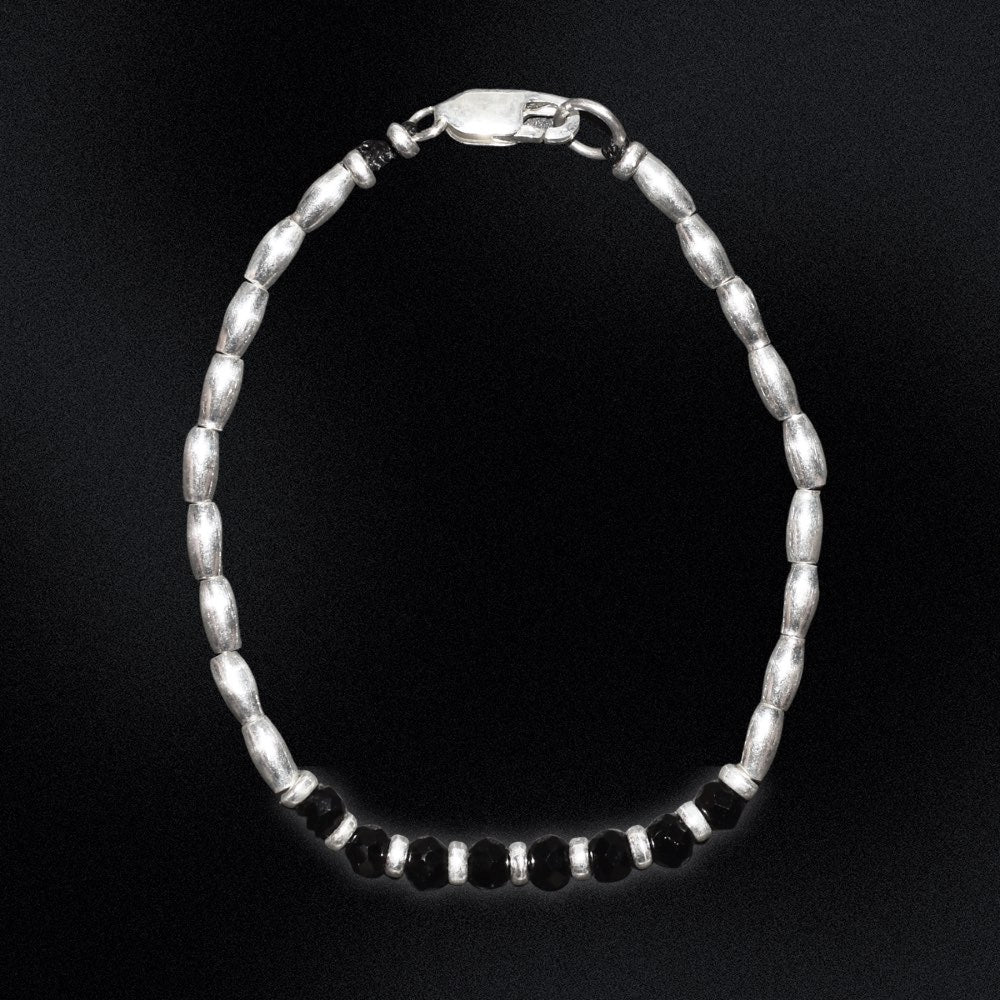 Introducing the Midnight Essence Silver Beaded Bracelet - the perfect accessory to complete any outfit. The centre detail of the bracelet features stunning faceted glass rondelle black beads that catch the light and sparkle brilliantly. Surrounding these gems are delicate silver beads, adding a touch of sophistication and elegance to the design.