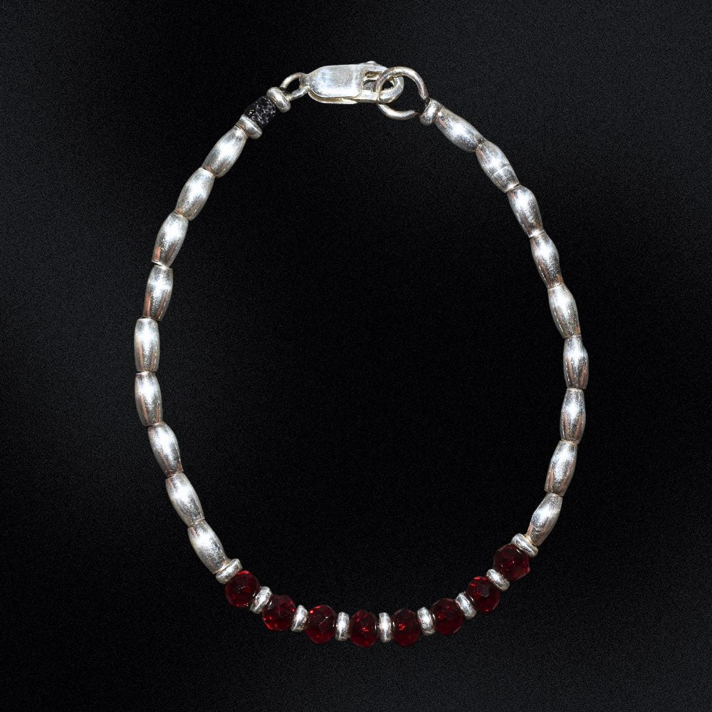 Introducing the Ruby Essence Silver Beaded Bracelet - the perfect accessory to complete any outfit. The centre detail of the bracelet features stunning faceted glass rondelle red beads that catch the light and sparkle brilliantly. Surrounding these gems are delicate silver beads, adding a touch of sophistication and elegance to the design.