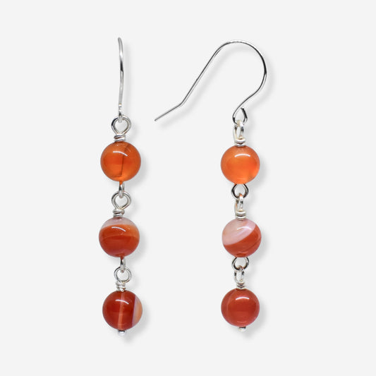 Pair of earrings with orange beads and silver hooks on a white background